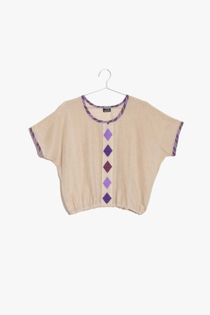 1) The Tami Top is a contemporary top that borrows details from the traditional Habesha Kemis. Casual yet colorful, this top will add a bright bohemian chic vibe to your closet.  2) Wear the Tami Top with a pair of high-waisted jeans or even with your favorite yoga pants. The cinched waist helps create structure while maintaining a relaxed fit.  3) Bright, punchy details along the neckline and sleeves, and the bold diamond pattern down the center makes this ecru top visually stunning