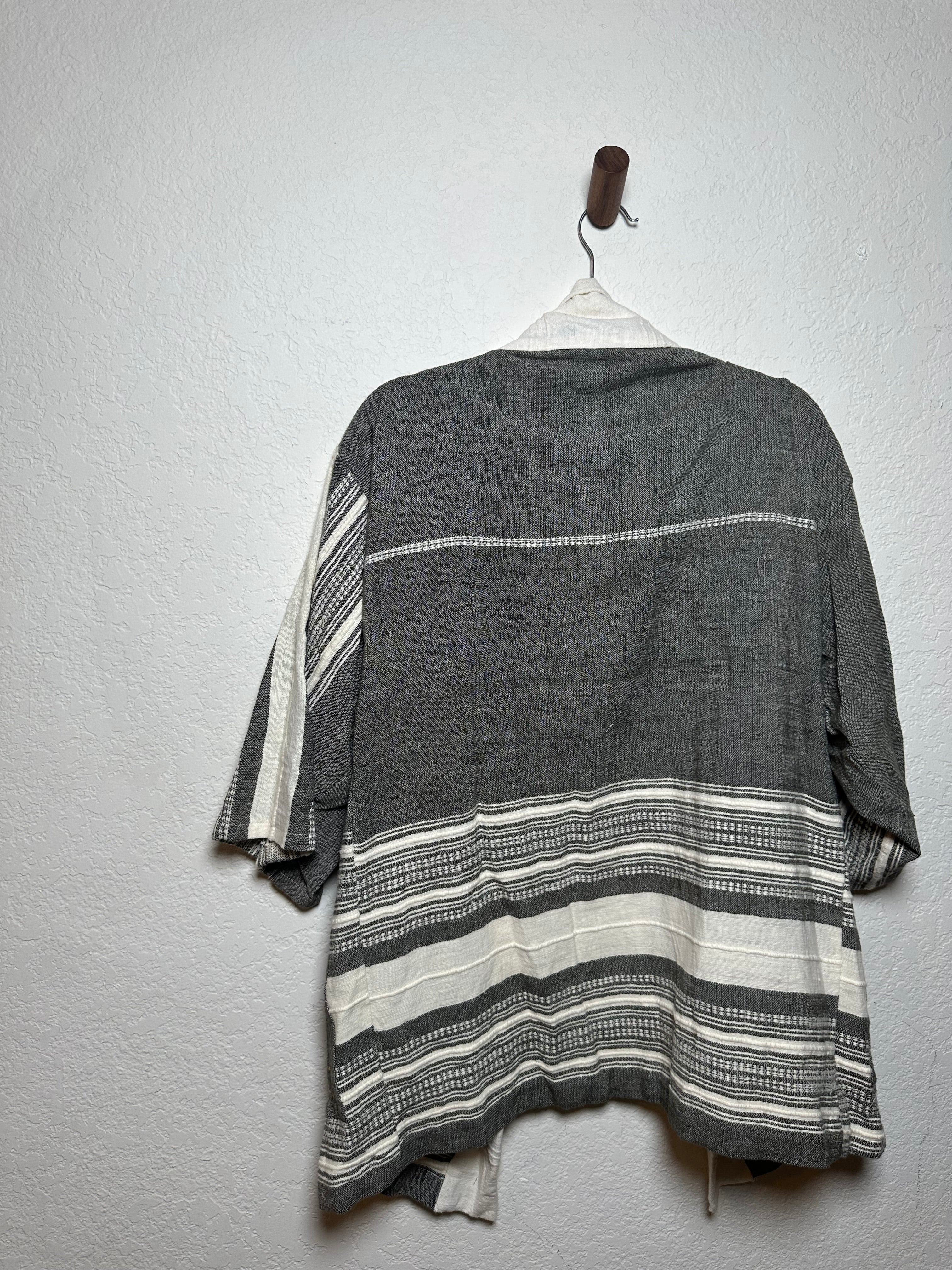 Gray and white striped fabric draped over a wooden rod on a light gray background