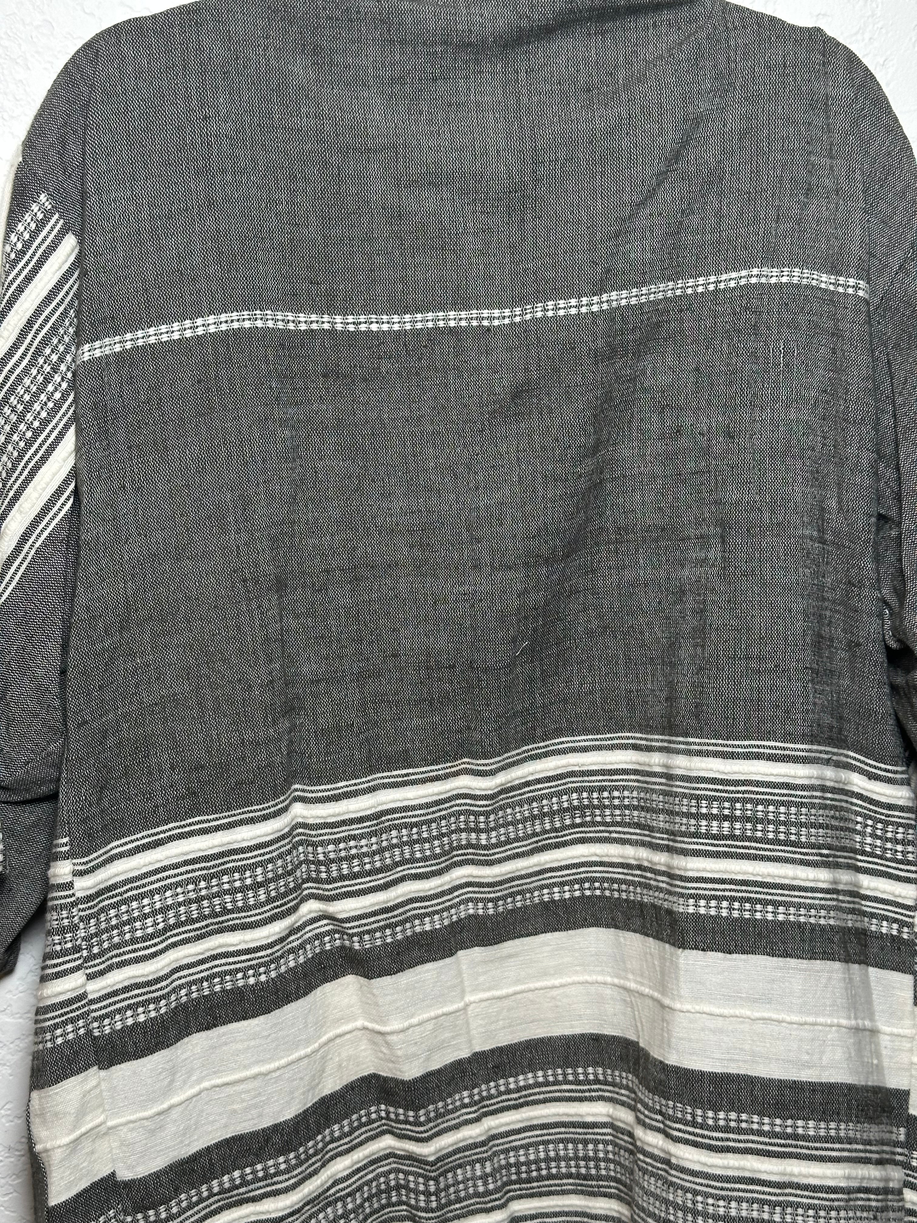 Model wearing the Zelalem Cardi in Obsidian Mist — a black-grey handwoven cotton cardigan draped open over a neutral outfit, photographed in natural light with a relaxed, effortless vibe