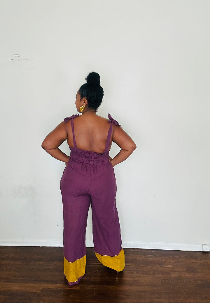 Sebie Jumpsuit in Purple Reign — 100% cotton, handmade in Ethiopia, featuring a regal royal purple tone with a rich golden hem.