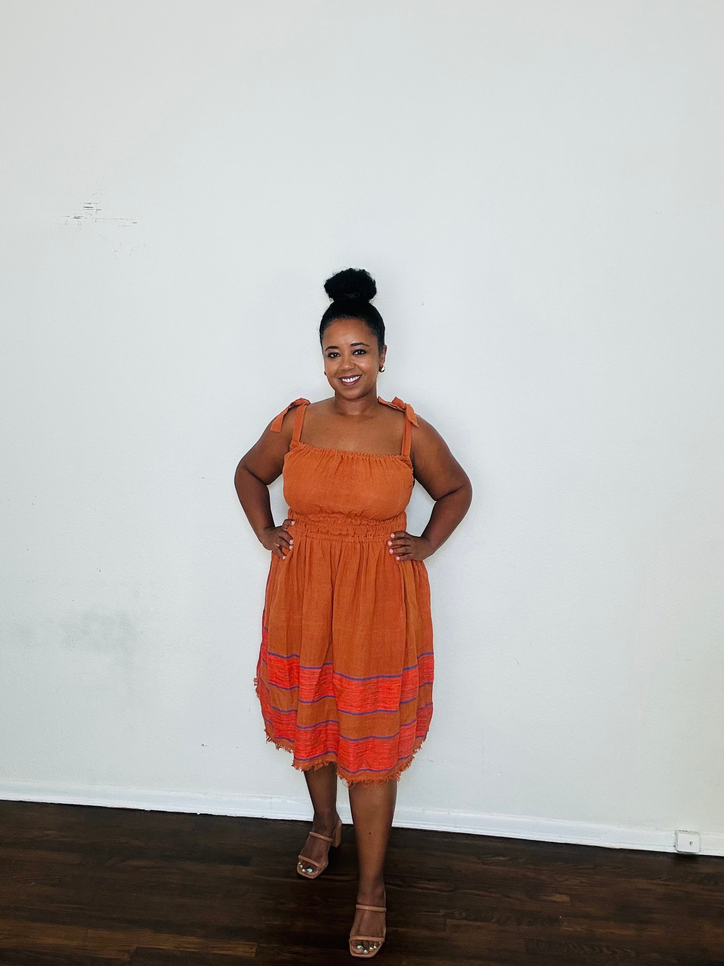 Gelila Dress Cinnabar Glow — handmade 100% cotton midi dress with straight neckline, adjustable straps, cinched waist, flowing skirt, and hidden pockets in a deep burnt orange tone.