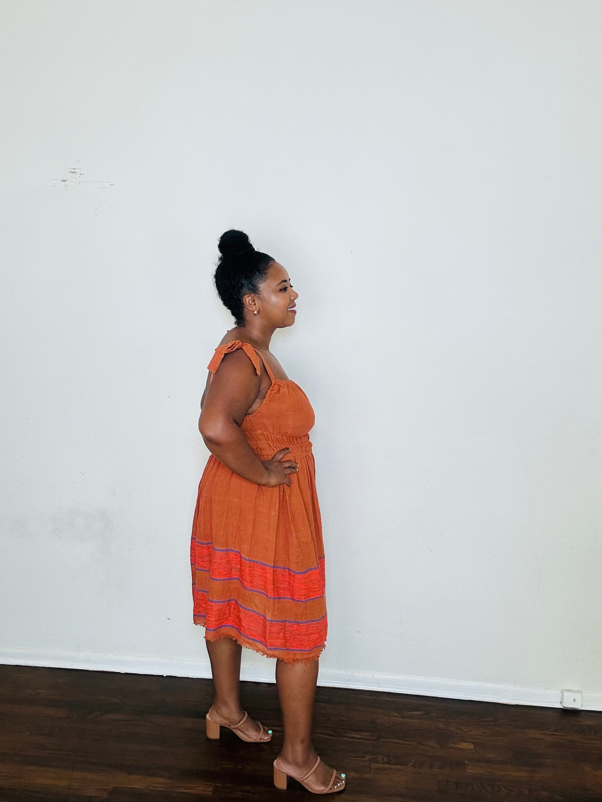 Gelila Dress Cinnabar Glow — handmade 100% cotton midi dress with straight neckline, adjustable straps, cinched waist, flowing skirt, and hidden pockets in a deep burnt orange tone.