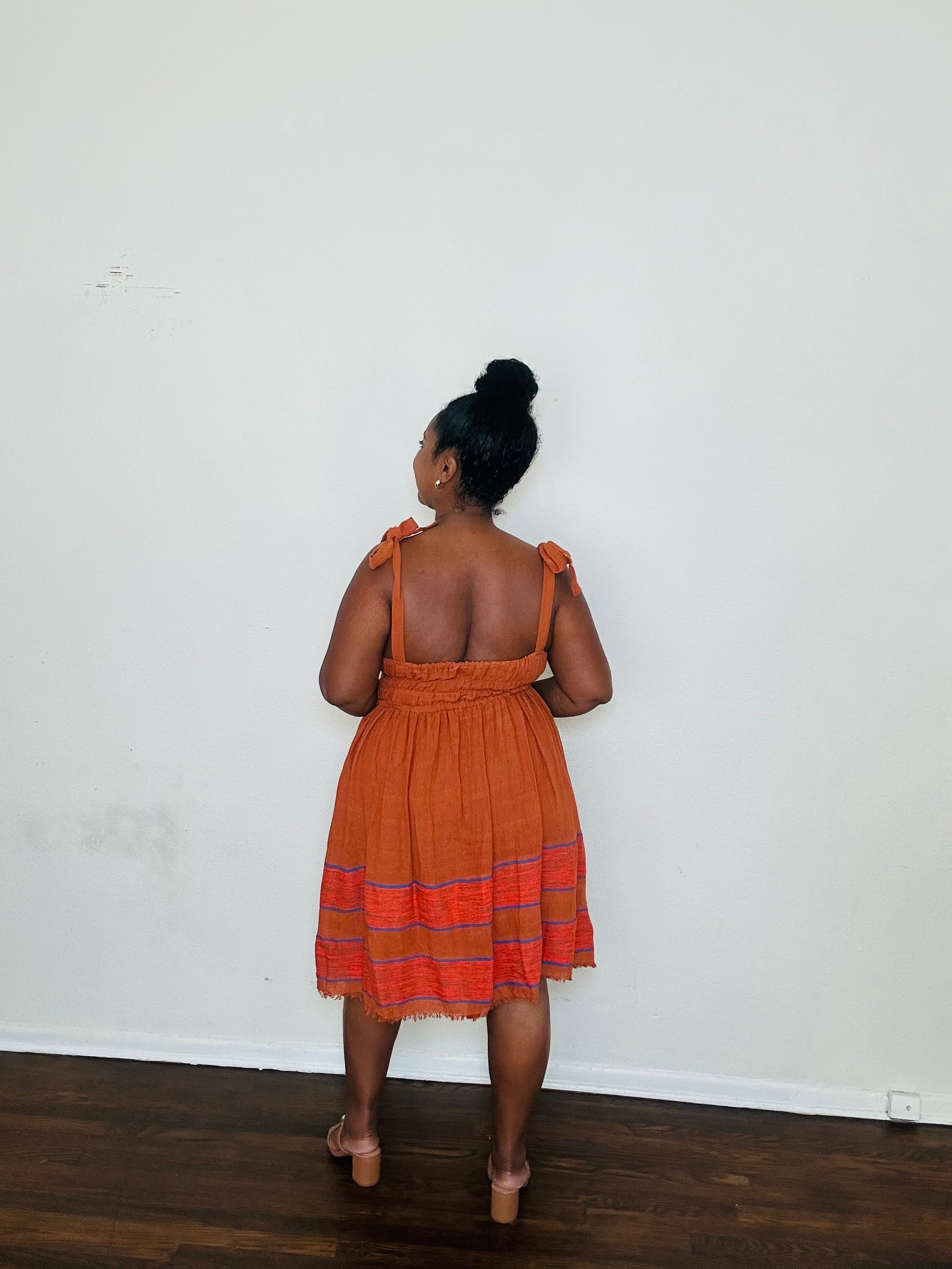 Gelila Dress Cinnabar Glow — handmade 100% cotton midi dress with straight neckline, adjustable straps, cinched waist, flowing skirt, and hidden pockets in a deep burnt orange tone.