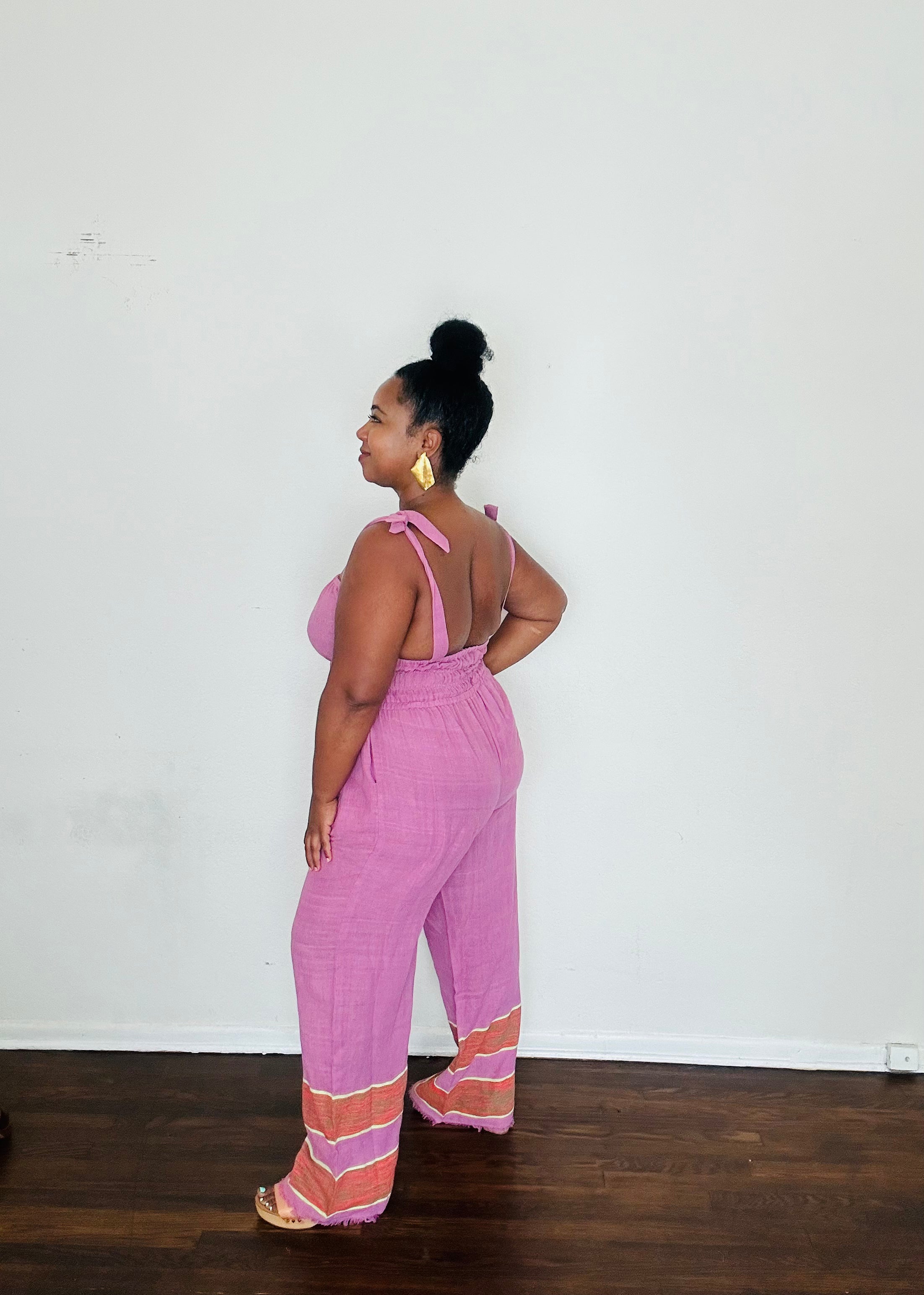 Handmade Lavender Sebie Jumpsuit in 100% cotton, featuring a flattering waist, adjustable straps, and deep pockets. Finished with a signature brown hem detailed with lime green accents for a bold, free-spirited LA style