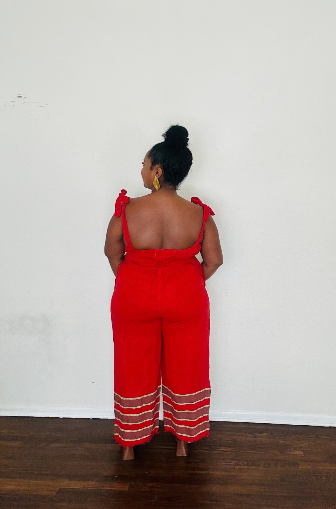 Handmade Cherry Red Sebie Jumpsuit in 100% cotton, from the back featuring a flattering waist, adjustable straps, and deep pockets. Finished with a signature brown hem detailed with lime green accents for a bold, free-spirited LA style 