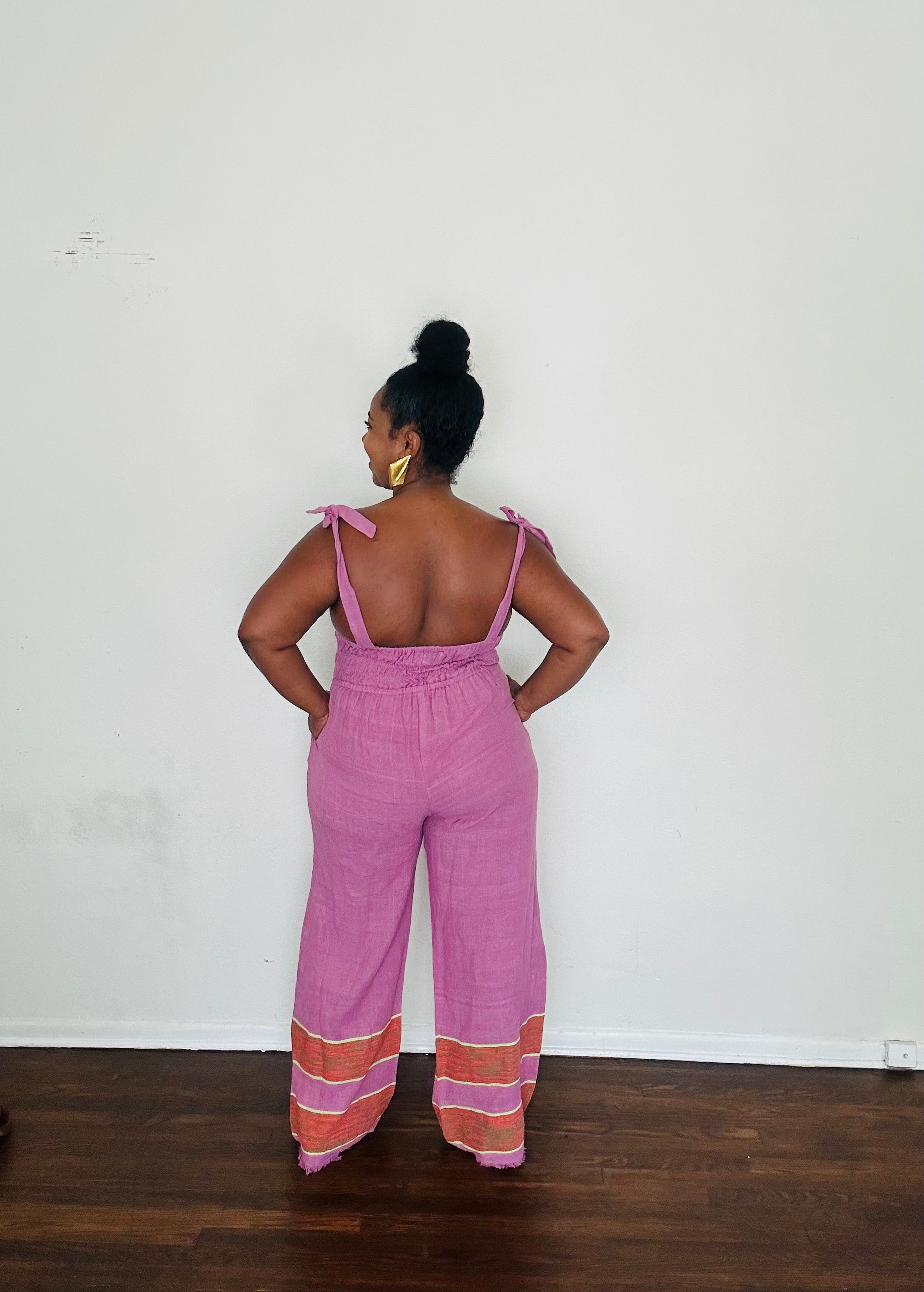 Handmade Lavender Sebie Jumpsuit in 100% cotton, featuring a flattering waist, adjustable straps, and deep pockets. Finished with a signature brown hem detailed with lime green accents for a bold, free-spirited LA style