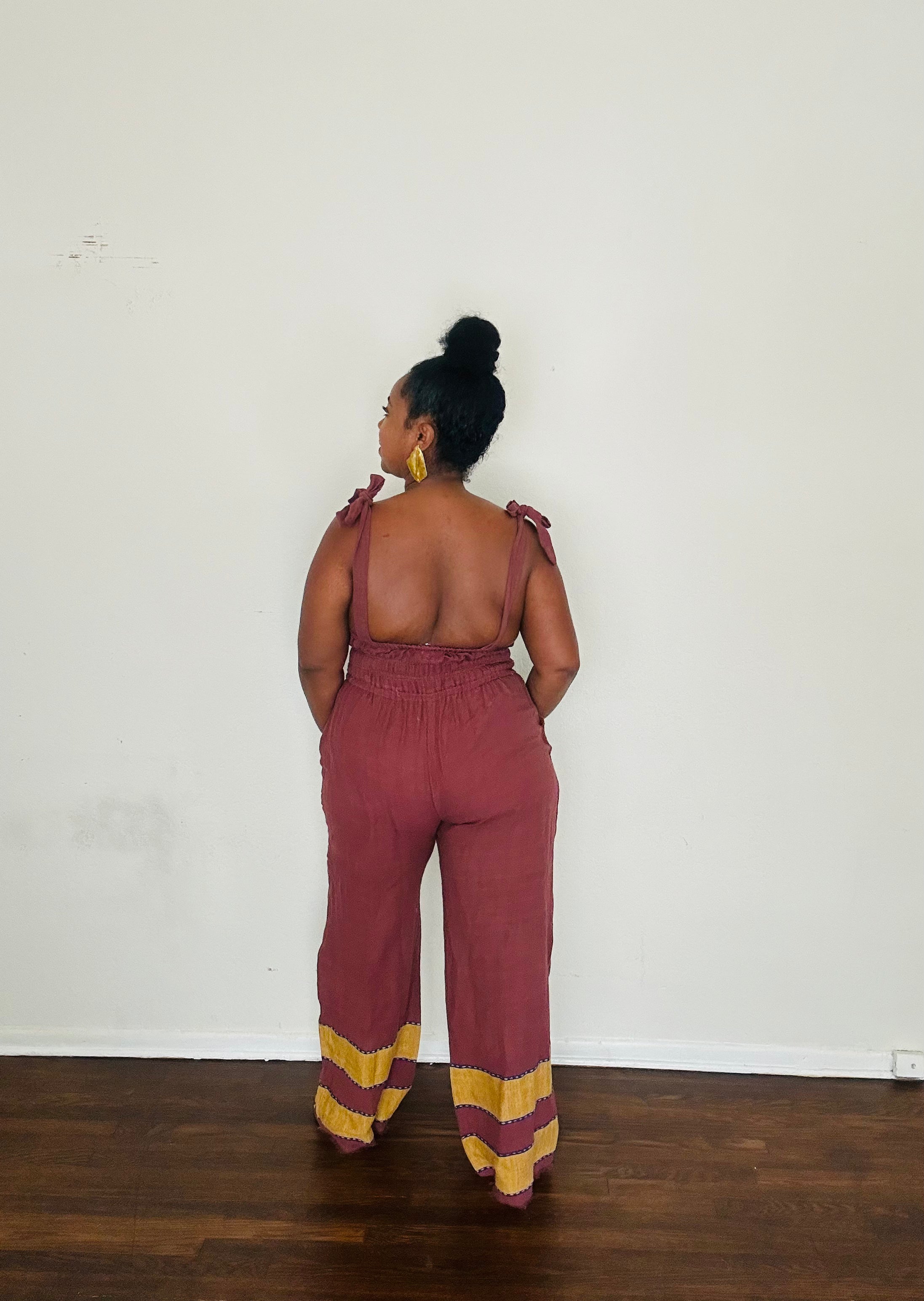 Handmade Plum Eclipse  Sebie Jumpsuit in 100% cotton, featuring a flattering waist, adjustable straps, and deep pockets. Finished with a signature brown hem detailed with lime green accents for a bold, free-spirited LA style