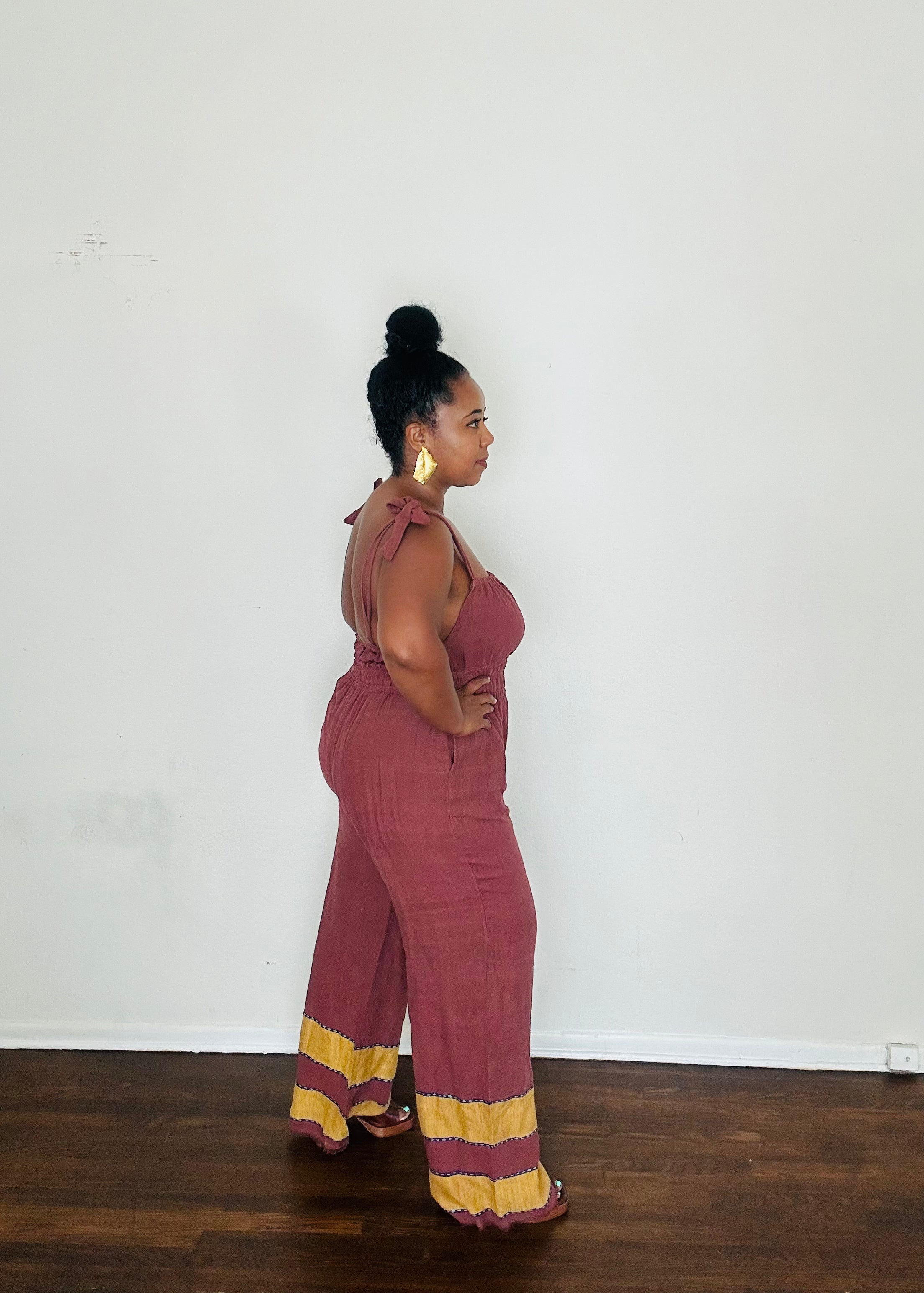 Handmade Plum Eclipse  Sebie Jumpsuit in 100% cotton, featuring a flattering waist, adjustable straps, and deep pockets. Finished with a signature brown hem detailed with lime green accents for a bold, free-spirited LA style