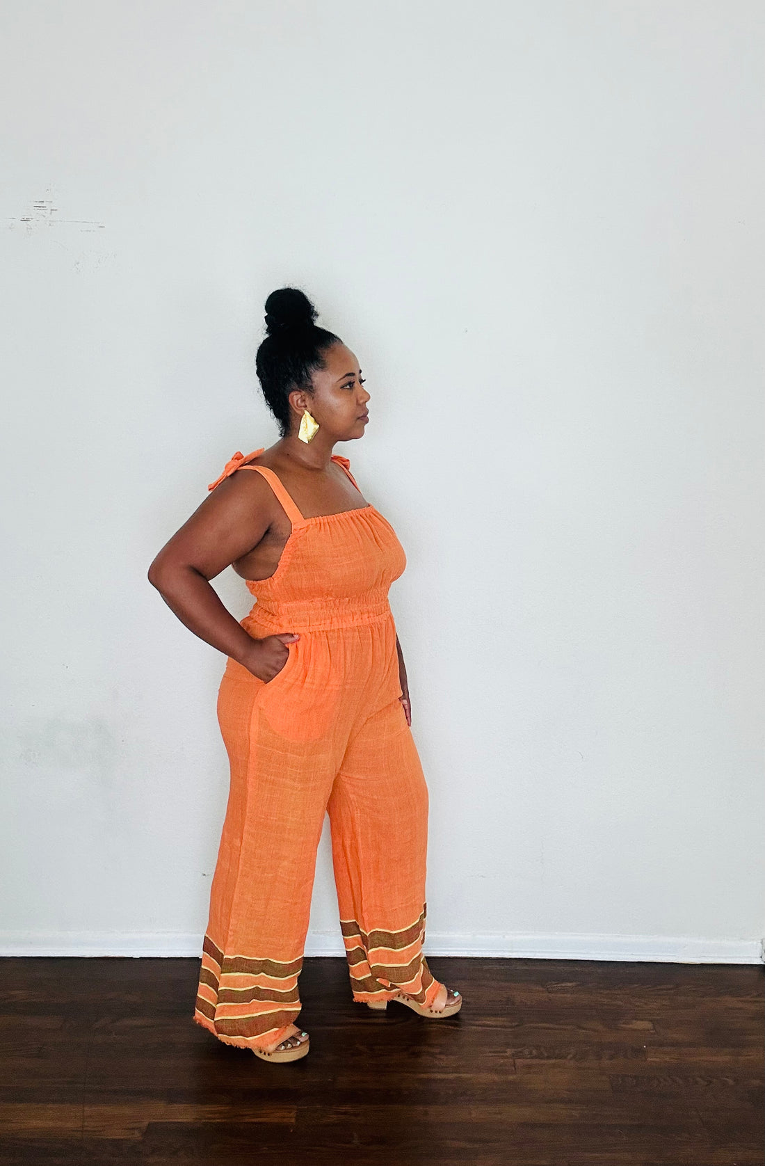 Handmade Orange Tangerine Dream Sebie Jumpsuit in 100% cotton, featuring a flattering waist, adjustable straps, and deep pockets. Finished with a signature brown hem detailed with lime green accents for a bold, free-spirited LA style